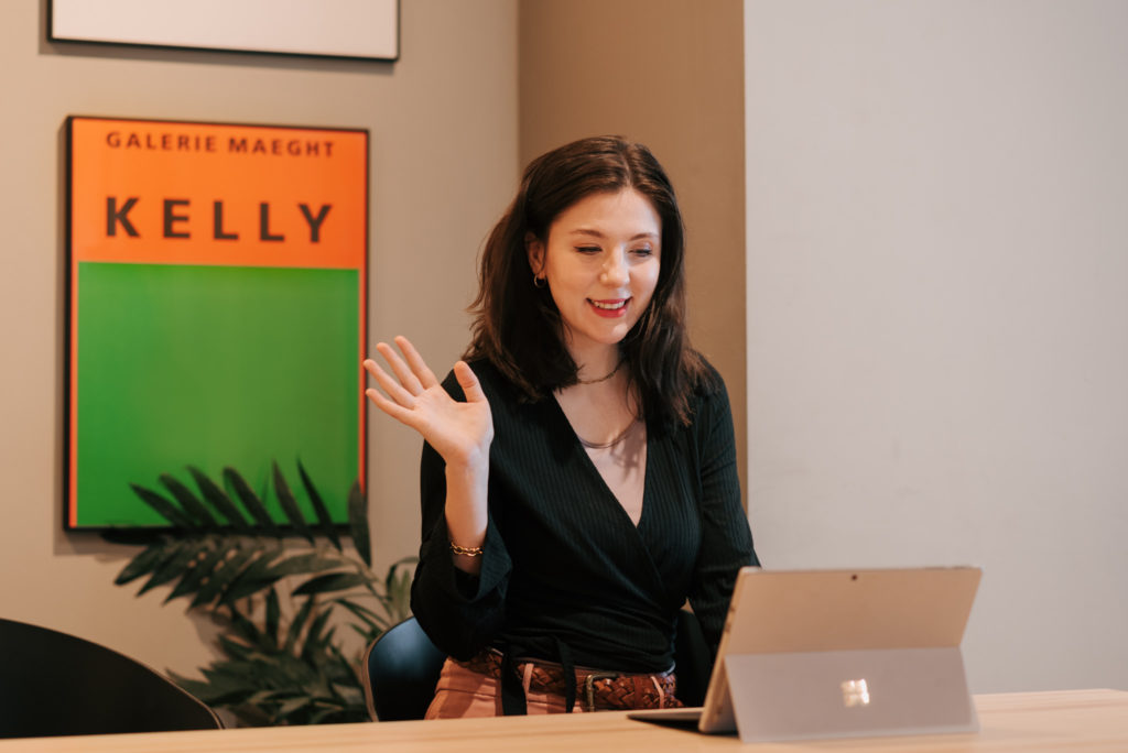 Katie Barber waving to her laptop on a zoom meeting